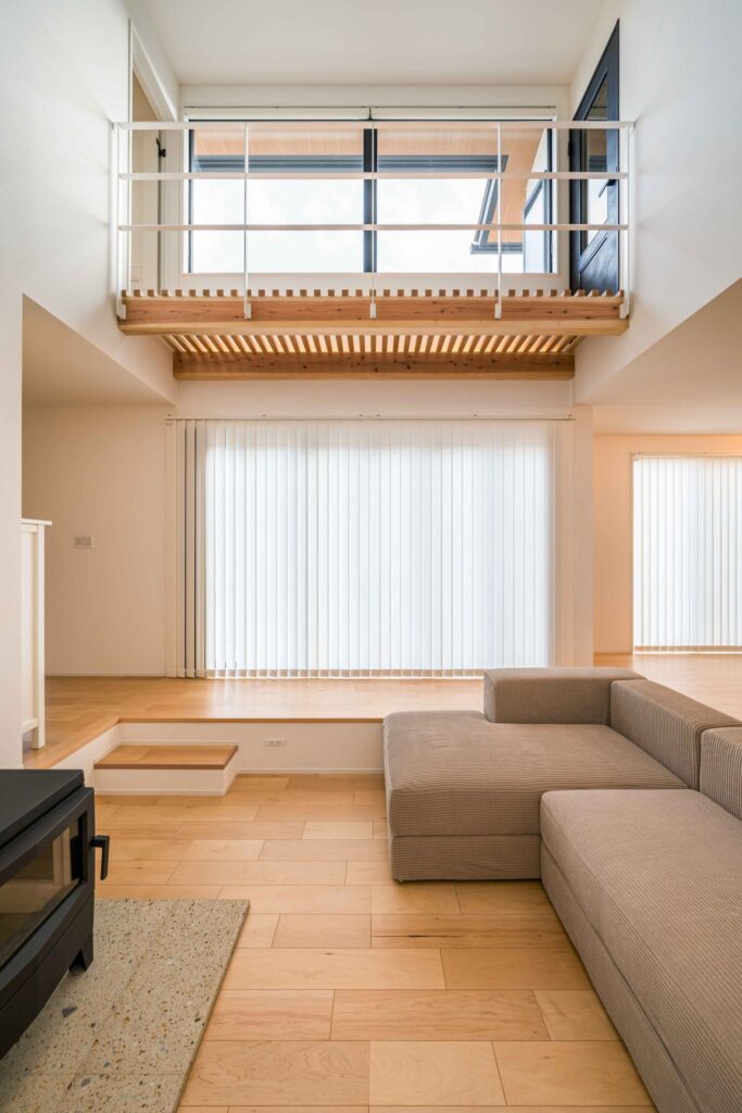 吹抜けから光が差し込む薪ストーブのあるリビング