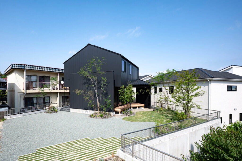 黒い外壁と庭が広がる個性的な敷地形状の住宅外観