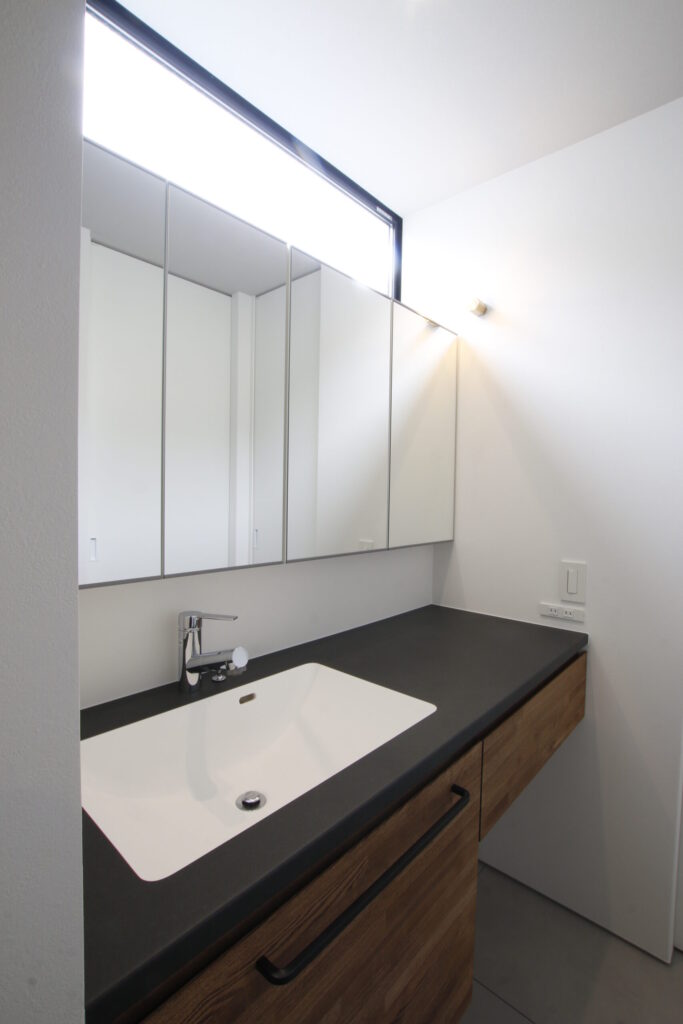 横長窓から自然光が入る洗面カウンター