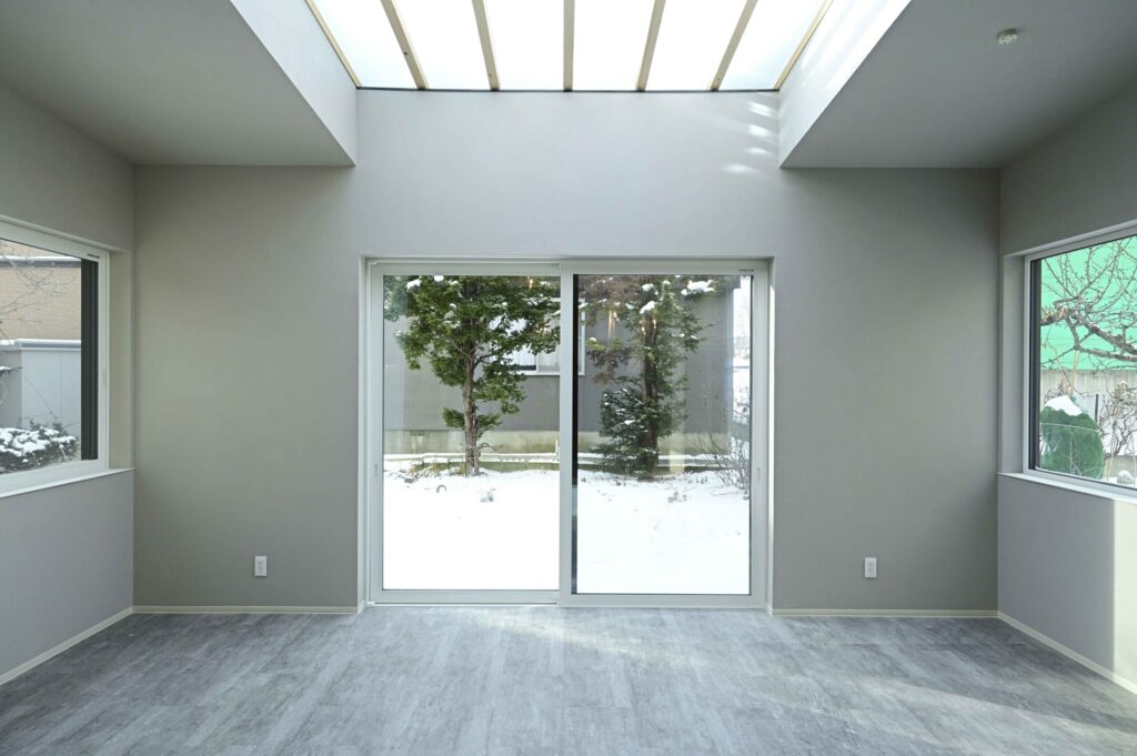 三方向の窓から光が差し込む白を基調としたLDK空間